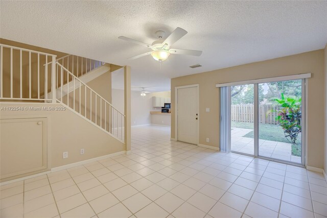 stairway with tile patterned flooring, ceiling fan, and a textured ceiling