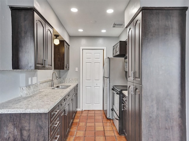 kitchen featuring light tile patterned flooring, appliances with stainless steel finishes, dark brown cabinets, and sink