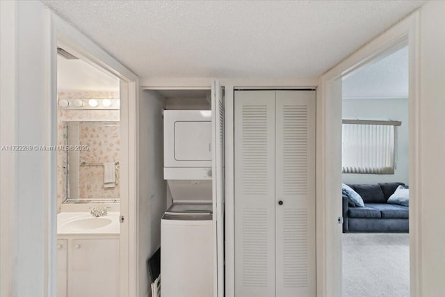 clothes washing area featuring carpet flooring, stacked washer and dryer, a textured ceiling, and sink