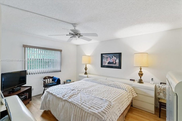 bedroom with a textured ceiling, light hardwood / wood-style floors, and ceiling fan