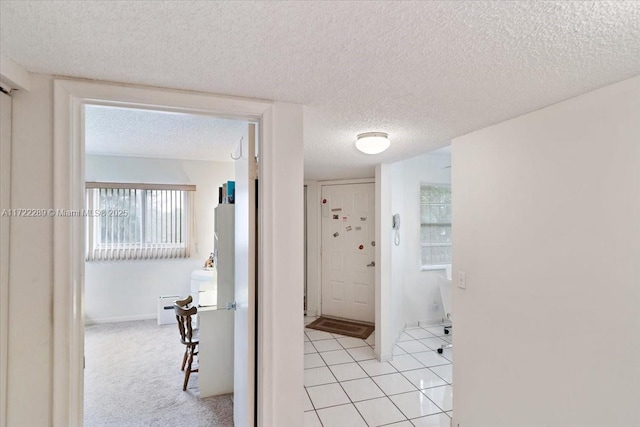 hall featuring light tile patterned floors and a textured ceiling