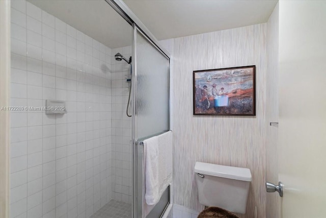 bathroom featuring toilet and a shower with shower door