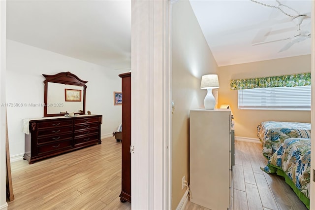 bedroom with lofted ceiling, light wood-type flooring, and baseboards