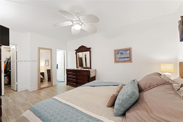 bedroom with ceiling fan, baseboards, light wood-style floors, a closet, and a walk in closet