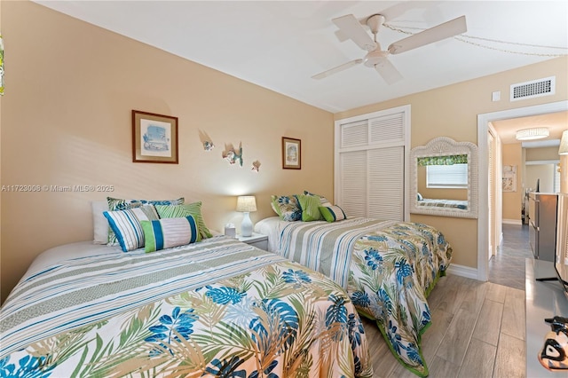 bedroom with baseboards, visible vents, a ceiling fan, wood finished floors, and a closet