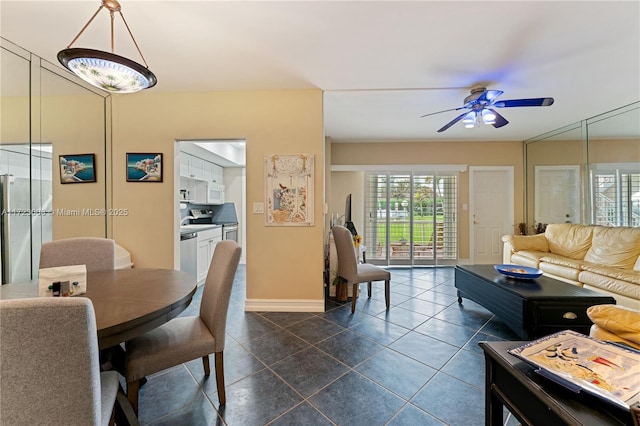 dining area featuring baseboards, a ceiling fan, and dark tile patterned flooring