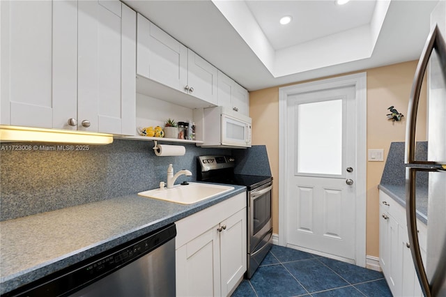 kitchen with a raised ceiling, decorative backsplash, sink, appliances with stainless steel finishes, and white cabinets