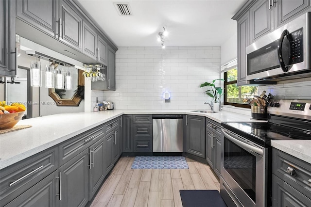 kitchen with backsplash, gray cabinetry, sink, and appliances with stainless steel finishes