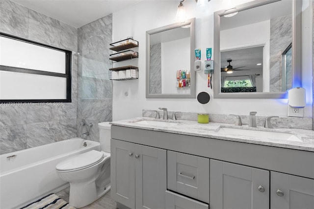 full bathroom with ceiling fan, toilet, tiled shower / bath, and vanity