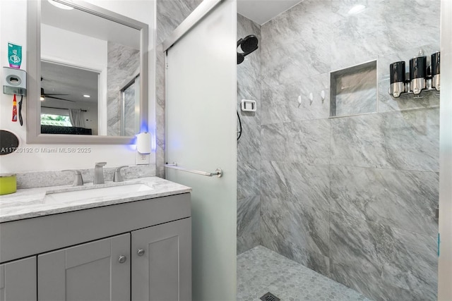 bathroom featuring tiled shower, vanity, and ceiling fan