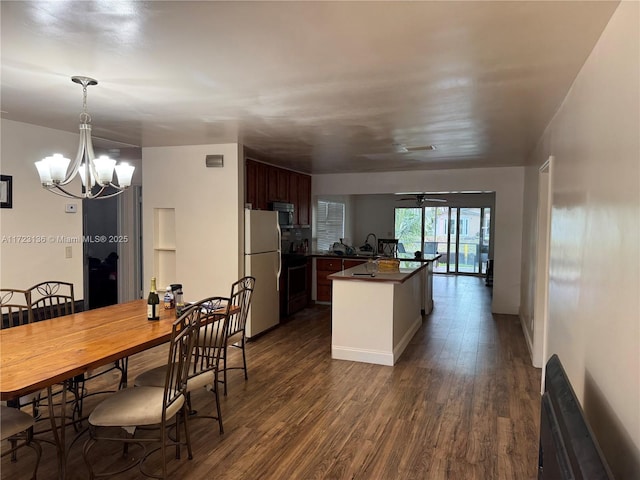 kitchen featuring dark wood-type flooring, electric range oven, white refrigerator, dark brown cabinets, and ceiling fan with notable chandelier