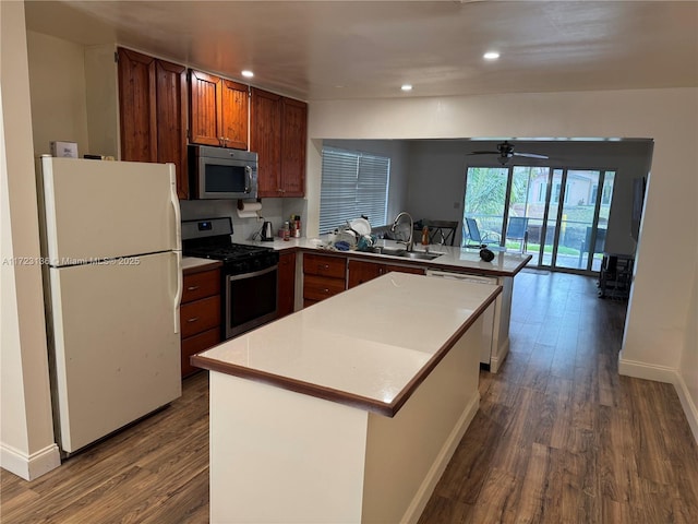 kitchen featuring appliances with stainless steel finishes, ceiling fan, dark wood-type flooring, sink, and a kitchen island