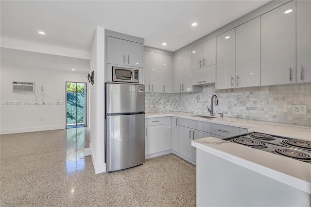 kitchen with decorative backsplash, gray cabinetry, stainless steel appliances, a wall unit AC, and sink