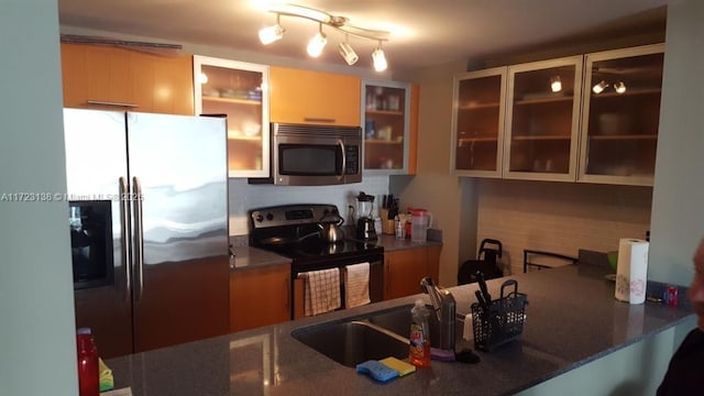 kitchen featuring sink, stainless steel appliances, dark stone counters, and tasteful backsplash