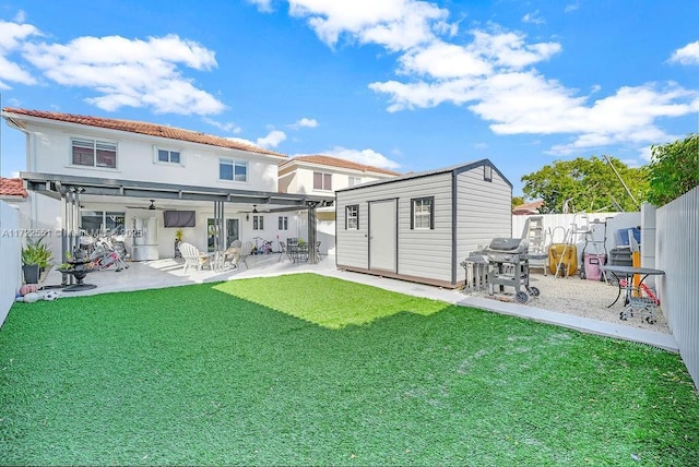 back of house with a yard, a patio, ceiling fan, and a storage shed