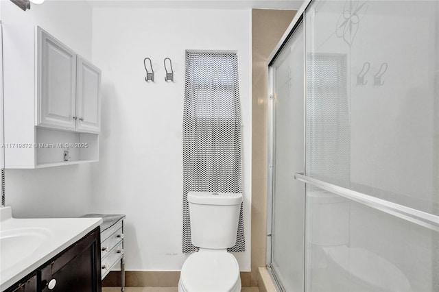 bathroom featuring a shower with shower door, toilet, and vanity