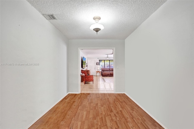 corridor featuring a textured ceiling and light hardwood / wood-style floors