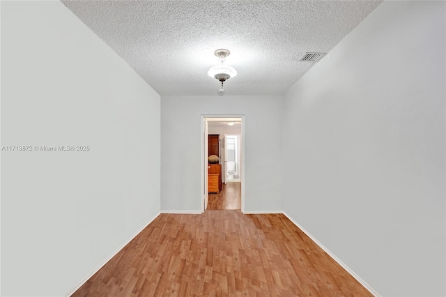 spare room featuring light wood-type flooring and a textured ceiling