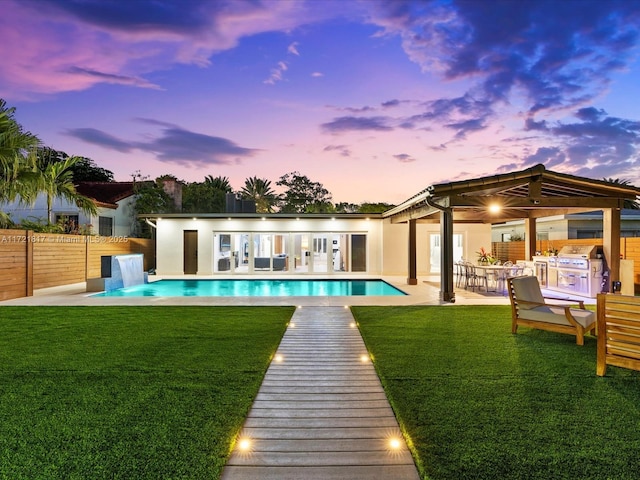 back house at dusk featuring a yard, a fenced in pool, and an outdoor structure