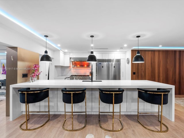 kitchen featuring sink, stainless steel built in refrigerator, kitchen peninsula, pendant lighting, and a breakfast bar area