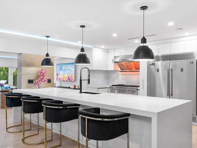 kitchen featuring white cabinetry, high quality appliances, sink, and hanging light fixtures