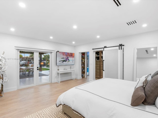 bedroom featuring access to exterior, a barn door, and light hardwood / wood-style floors