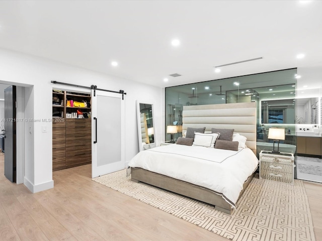 bedroom with a barn door and light hardwood / wood-style floors