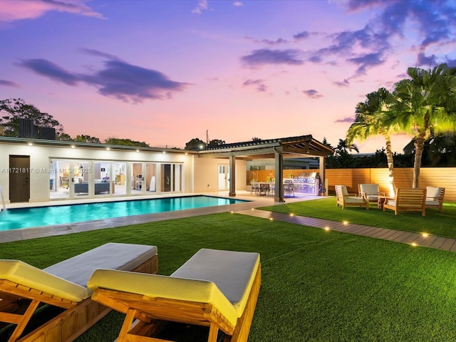 pool at dusk featuring an outdoor living space, a yard, and a patio