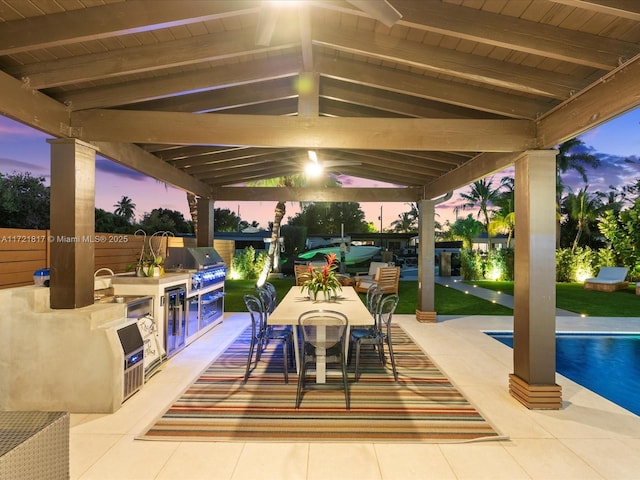 patio terrace at dusk with sink, a gazebo, an outdoor kitchen, and a grill