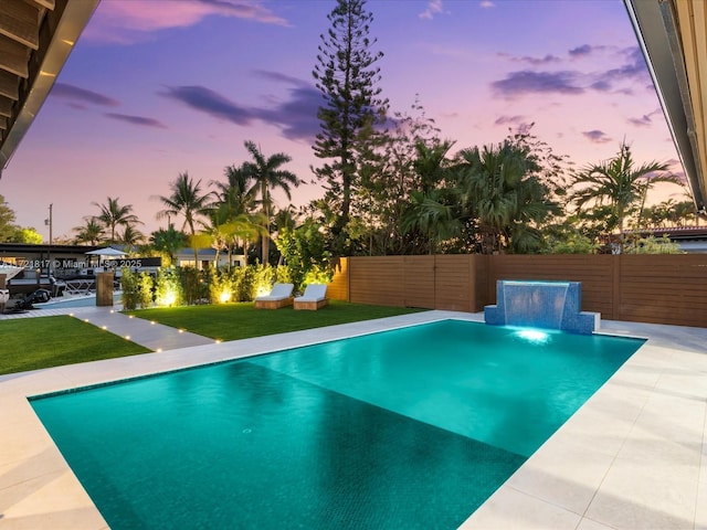 pool at dusk featuring pool water feature