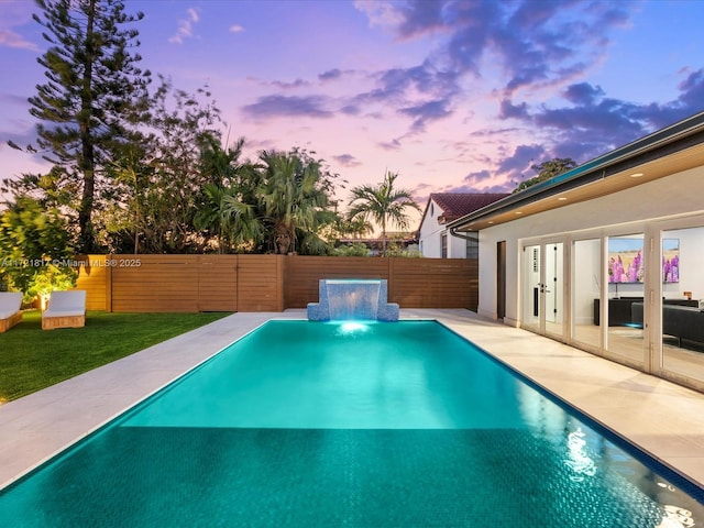 pool at dusk with pool water feature and a jacuzzi