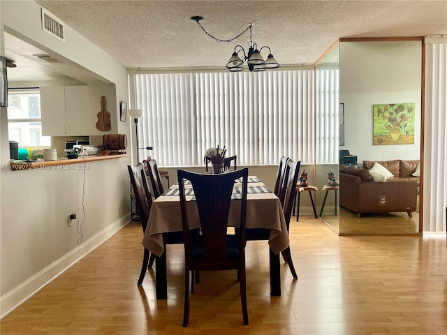 dining room featuring a textured ceiling, light hardwood / wood-style flooring, and a notable chandelier