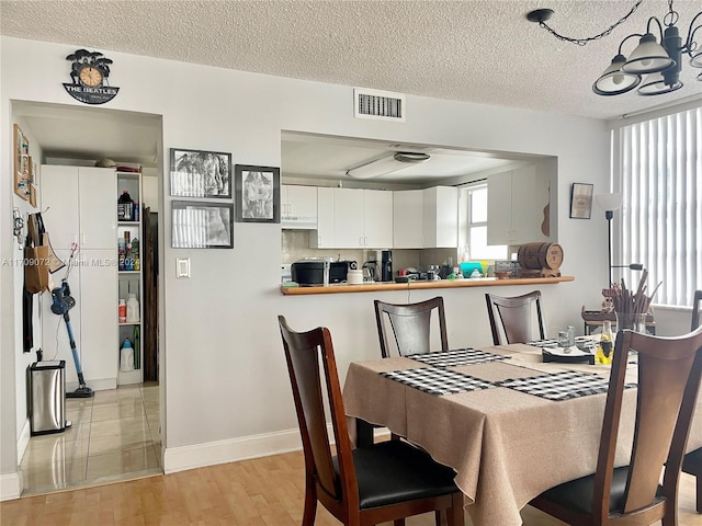 dining room featuring light wood-type flooring and a textured ceiling