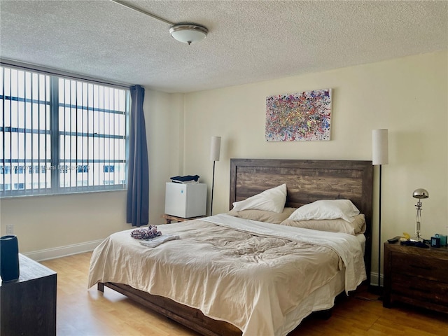 bedroom with hardwood / wood-style flooring, a textured ceiling, and multiple windows