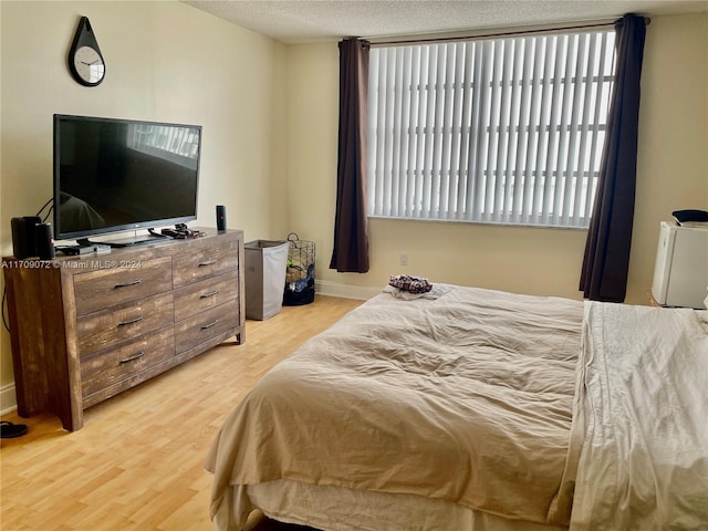 bedroom with a textured ceiling and light hardwood / wood-style floors