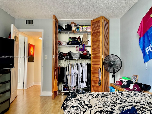 bedroom featuring light hardwood / wood-style floors, a textured ceiling, and a closet