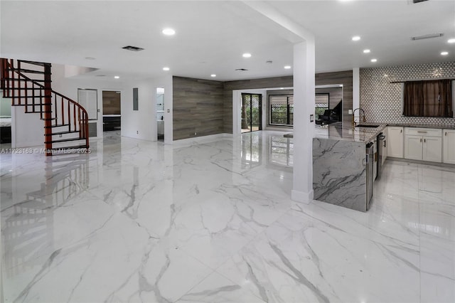 kitchen featuring light stone countertops, white cabinetry, and sink