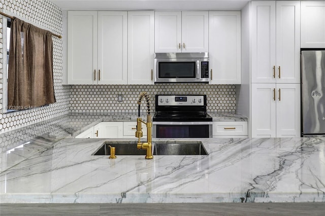 kitchen with appliances with stainless steel finishes, white cabinets, and light stone countertops