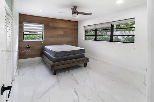 bedroom featuring ceiling fan and wood walls