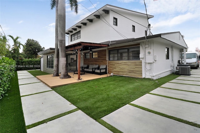 back of property featuring central air condition unit and a yard