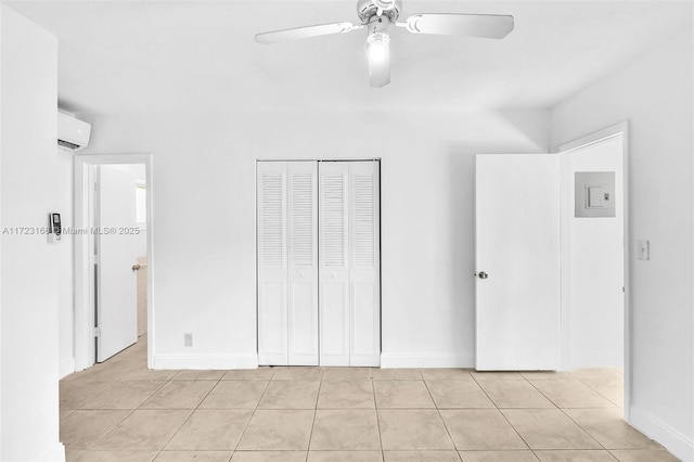 unfurnished bedroom featuring ceiling fan, light tile patterned flooring, an AC wall unit, and a closet