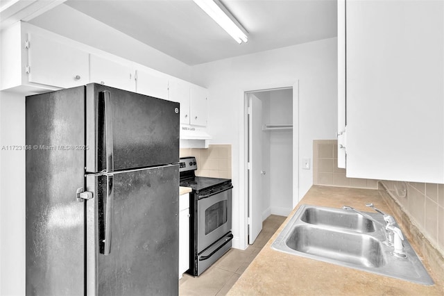 kitchen featuring tasteful backsplash, sink, black appliances, light tile patterned floors, and white cabinetry