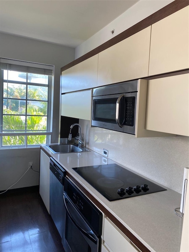 kitchen with white cabinetry, a healthy amount of sunlight, sink, and black appliances