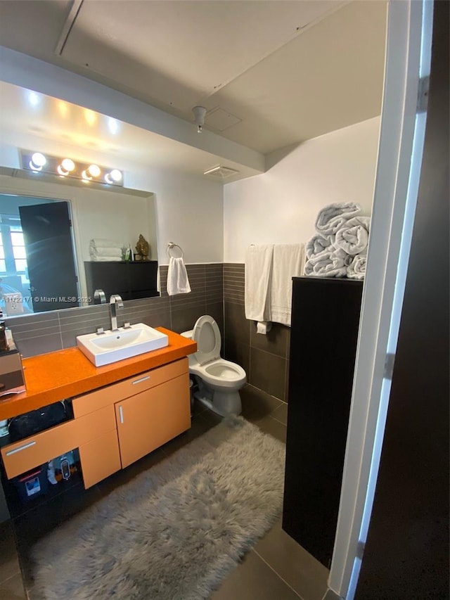 bathroom with tile patterned floors, vanity, tile walls, and toilet