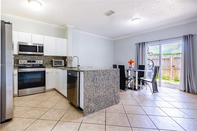 kitchen featuring light tile patterned floors, appliances with stainless steel finishes, white cabinets, stone countertops, and kitchen peninsula