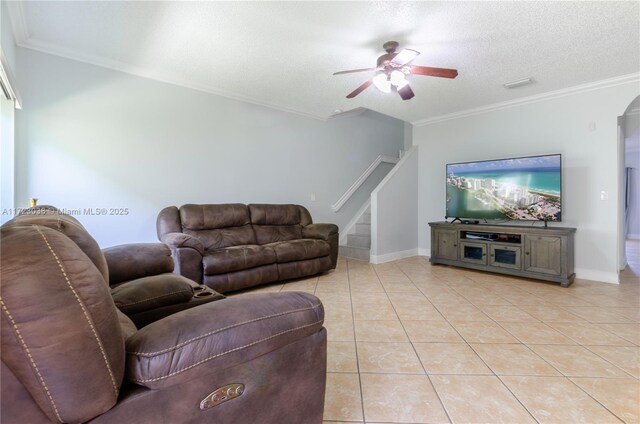 living room featuring ceiling fan, ornamental molding, a textured ceiling, and light tile patterned floors