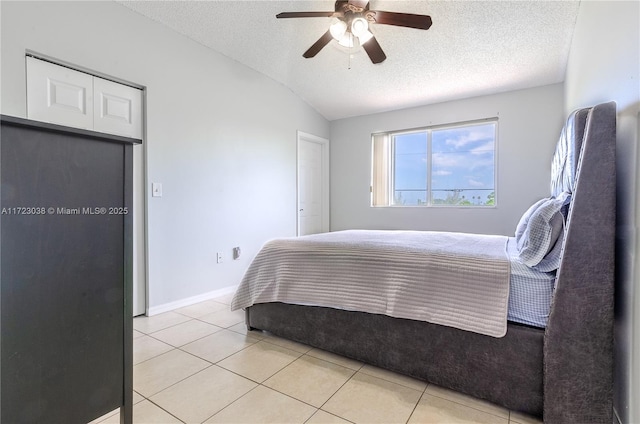 bedroom with lofted ceiling, a textured ceiling, and light tile patterned flooring