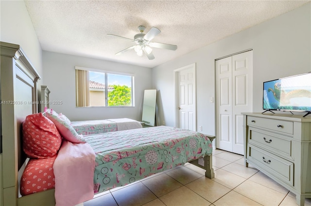 tiled bedroom with ceiling fan, a closet, and a textured ceiling