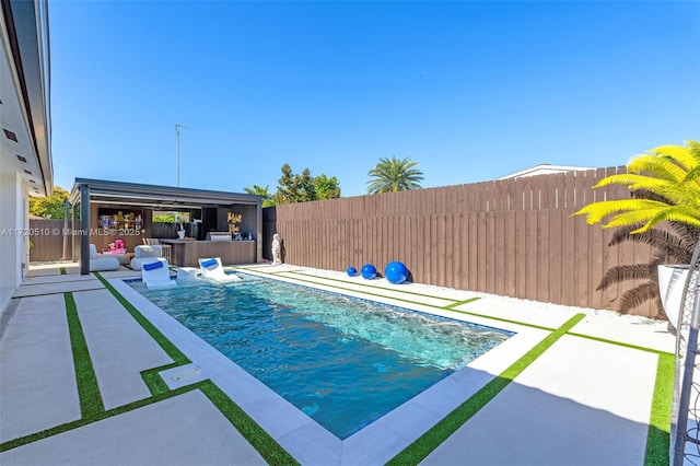 view of pool with pool water feature, an outdoor kitchen, and a patio area