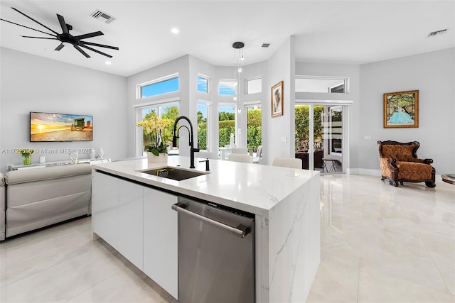 kitchen with stainless steel dishwasher, sink, decorative light fixtures, a center island with sink, and white cabinets